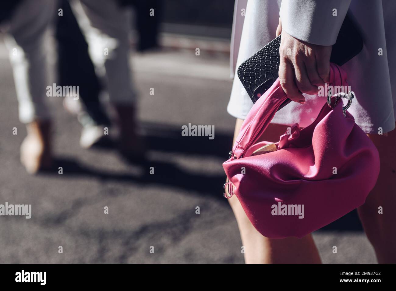 Milan, Italy - February 26, 2022: Woman in stylish gray coat with pink handbag. Stock Photo