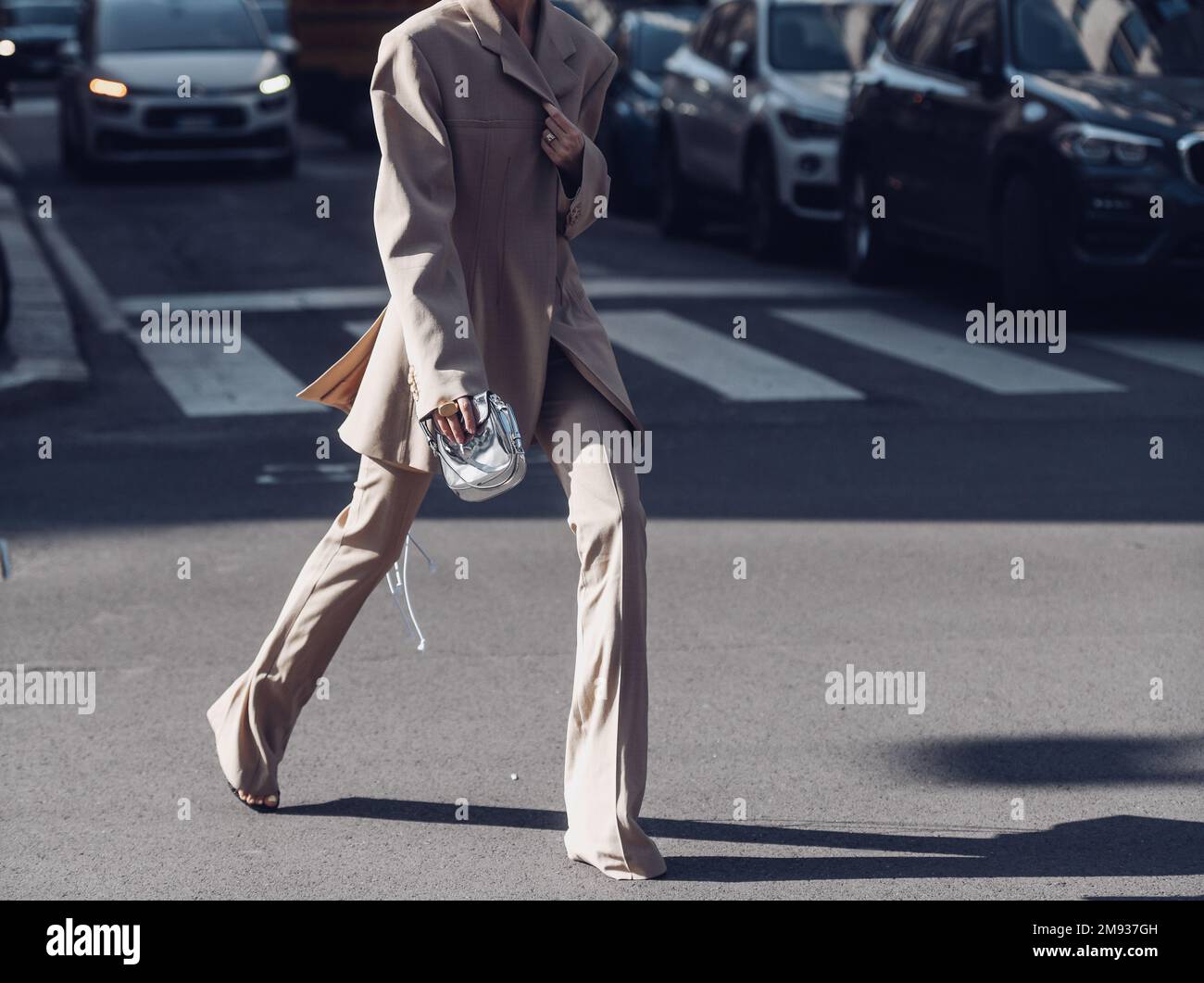 Milan, Italy - February 26, 2022: Woman in stylish beige suit adjusting jacket. Stock Photo