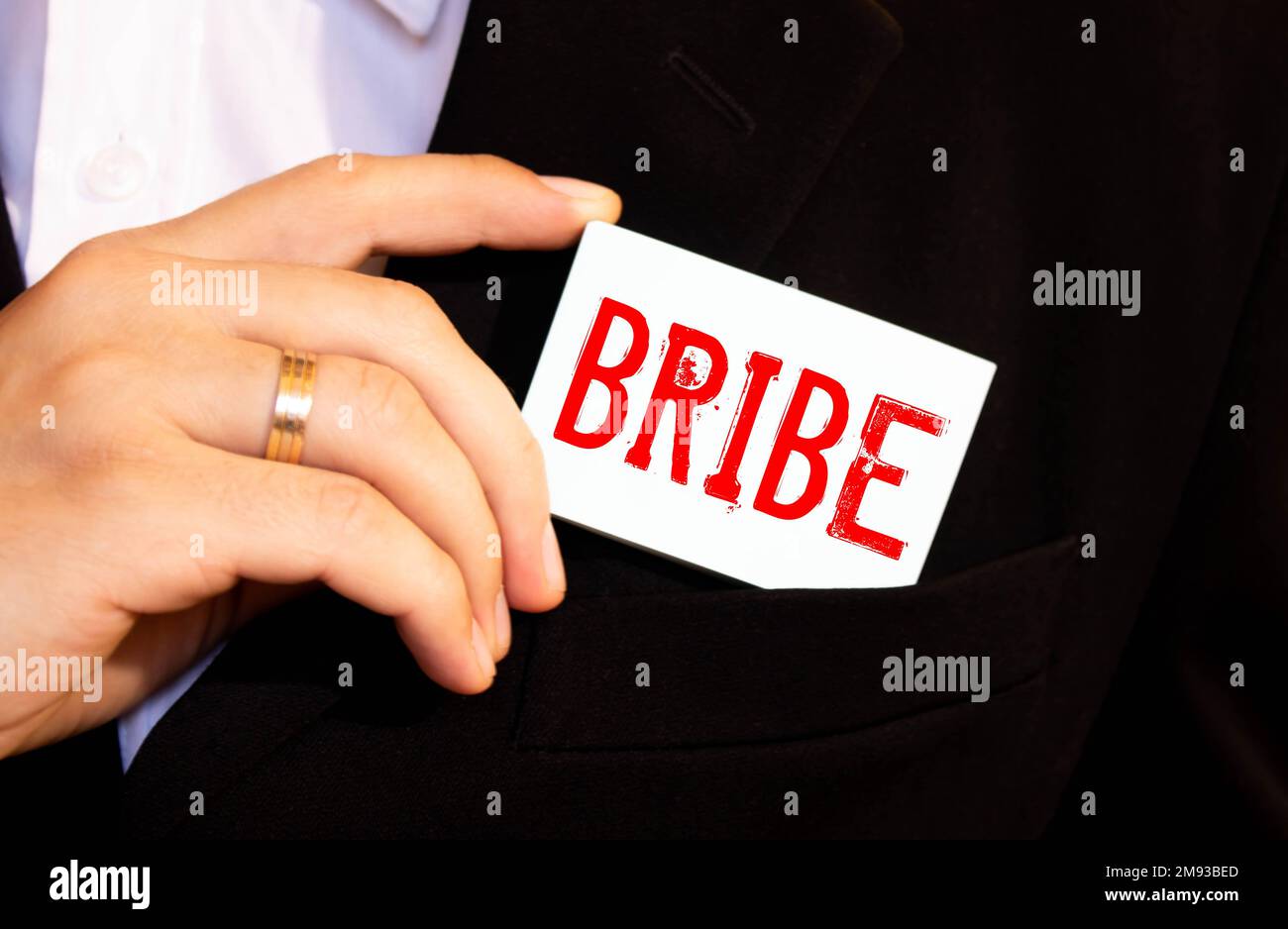 a person puts in his pocket a card labeled BRIBE Stock Photo
