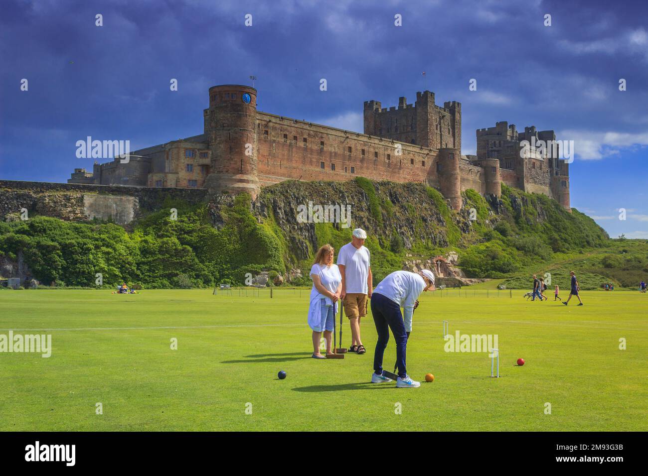 Group enjoying croquet in shadow of Bamburgh Castle Stock Photo