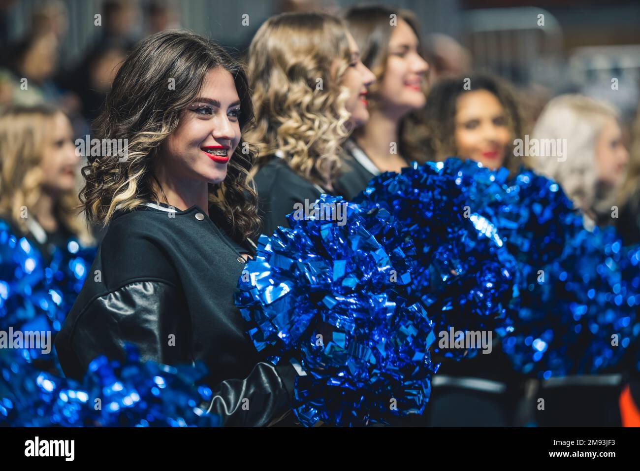 Medium shot of a group of cheerleaders cheering and holding blue pompoms. Sport concept. High