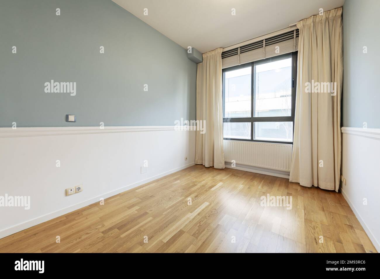Empty living room with metal radiator under the window with heavy