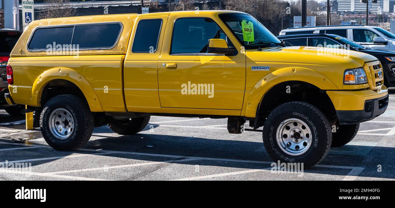 A used, yellow Ford Ranger pick up truck with a cap for sale at a