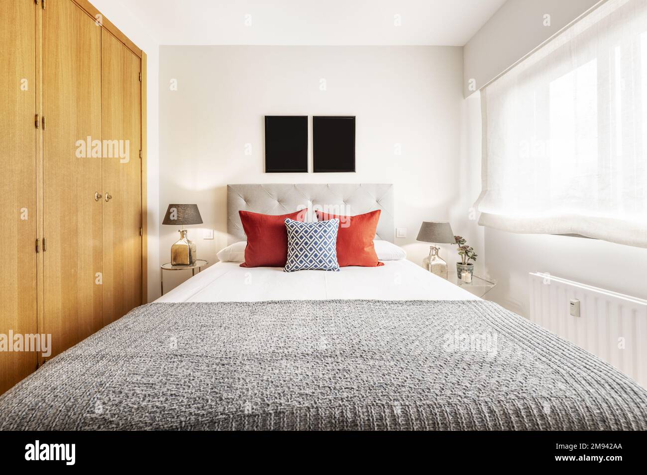 Double bedroom with a bed with a gray headboard, twin lamps on the