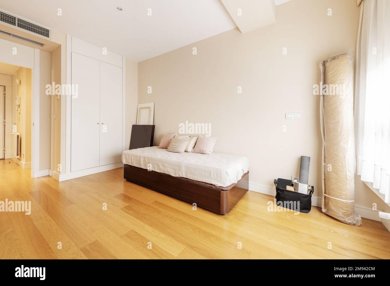 Bedroom with a single bed with a wooden sofa and various cushions and