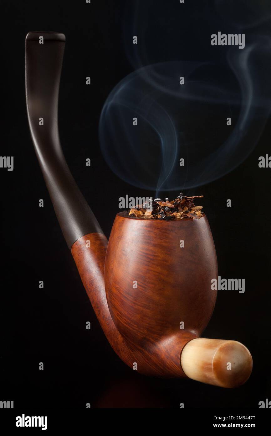 LIt Wooden Elegant Brown Tobacco pipe with tobacco in dark background