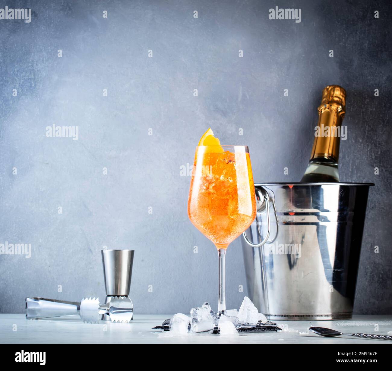 Aperol spritz classic alcoholic cocktail in wine glass, summer Italian low alcohol cold drink. Prosecco bottle in ice bucket on gray bar counter backg Stock Photo