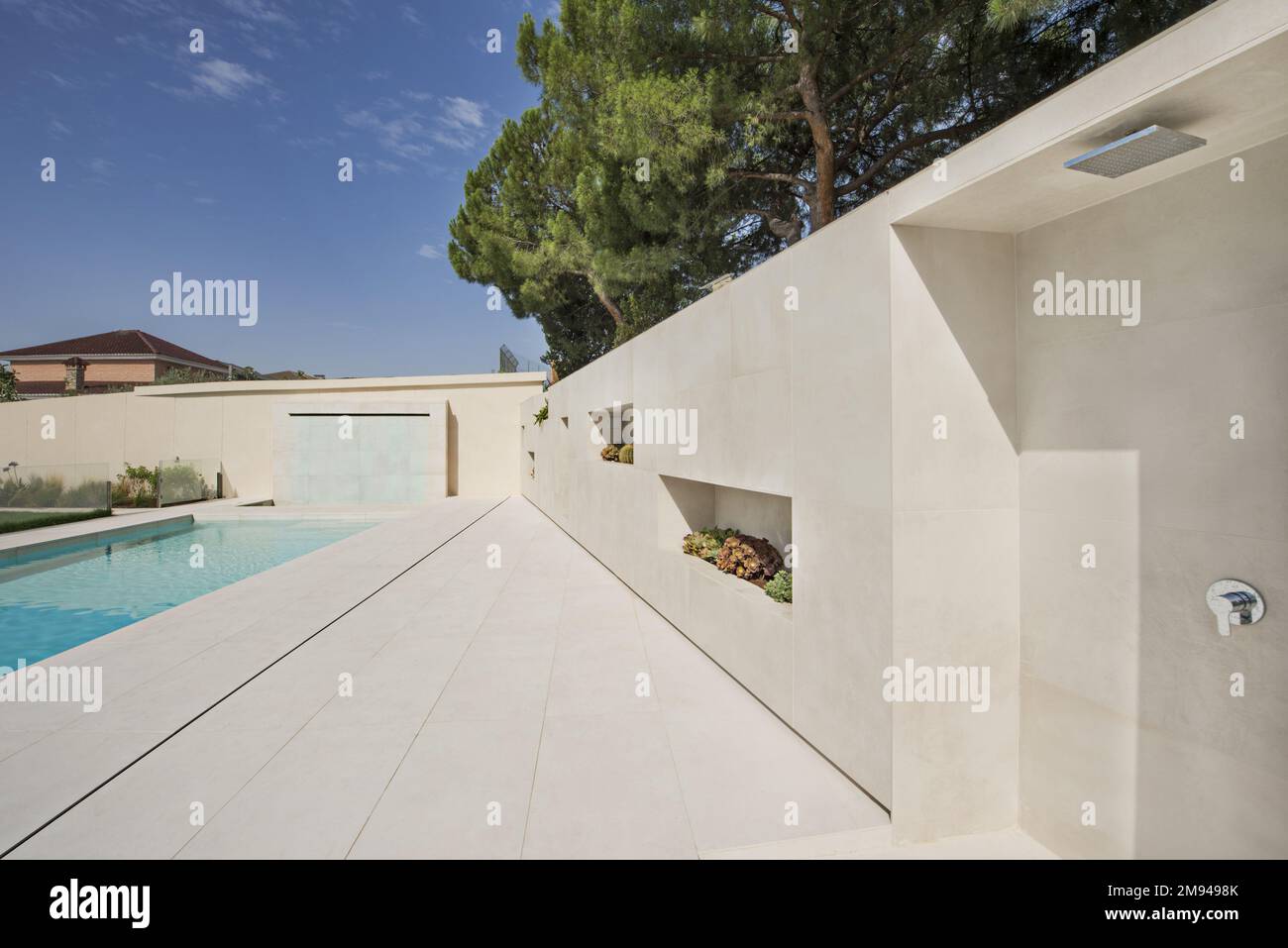 https://c8.alamy.com/comp/2M9498K/shower-area-of-a-swimming-pool-with-white-marble-tiles-and-wall-of-the-same-material-with-niches-for-plants-2M9498K.jpg