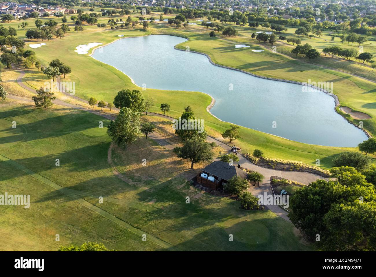 Aerial top view of a green park on the coast of lake. The water in the ...