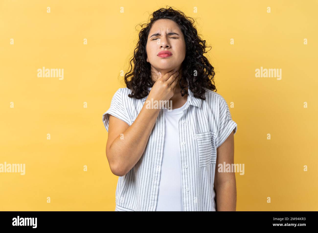 Portrait of sick unhealthy woman with dark wavy hair touching her neck