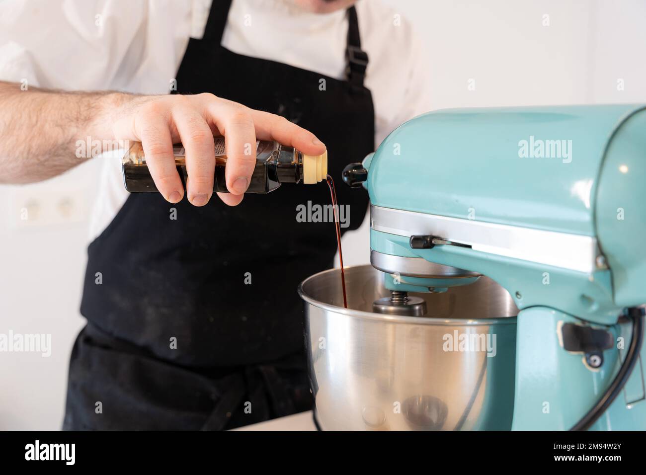 A man baker cooking a red velvet cake at home, preparing the cake by adding vanilla cuttlefish in the food processor, work at home Stock Photo