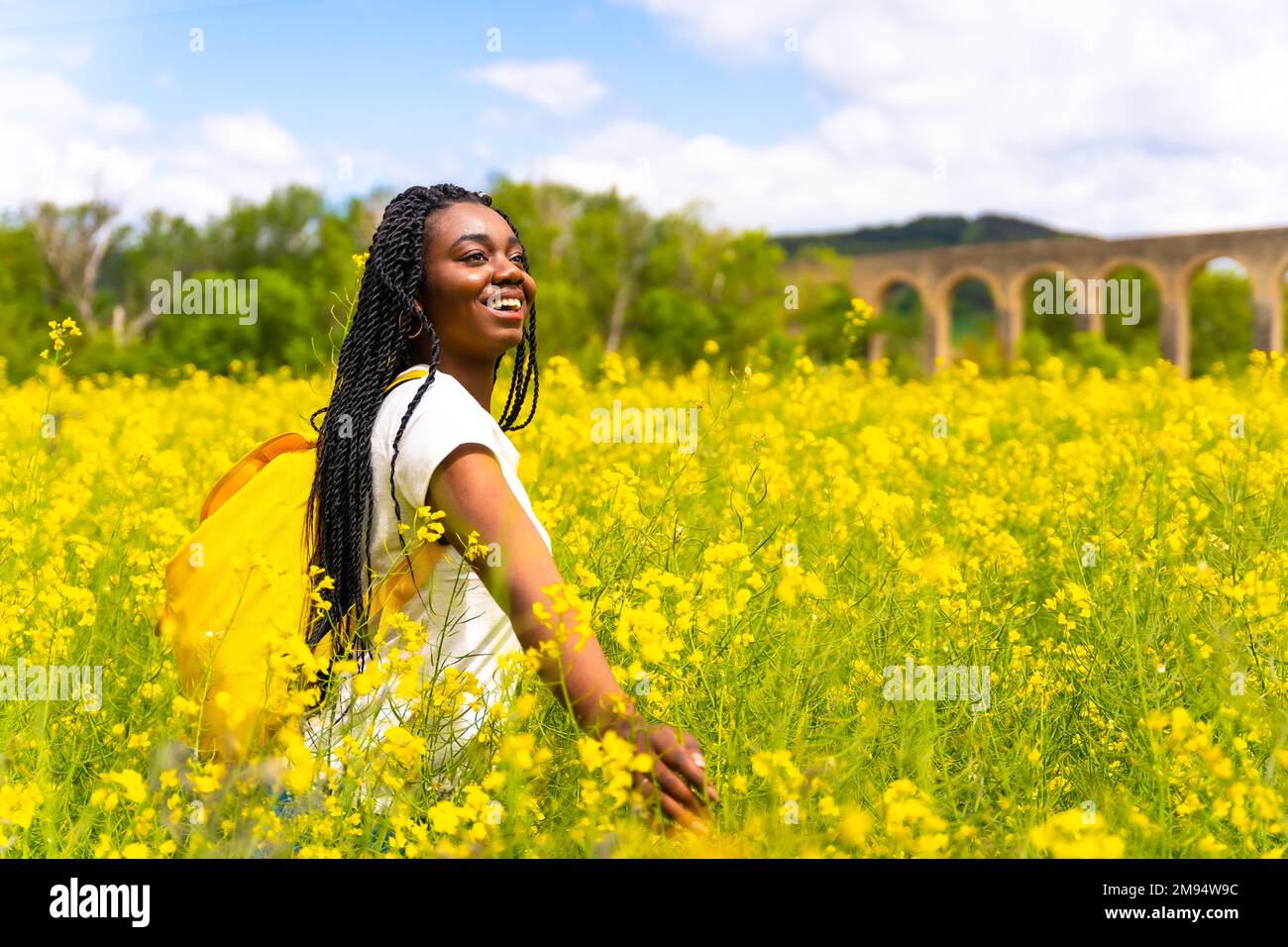 Enjoying Freedom A Black Ethnic Girl With Braids A Traveler In A Field Of Yellow Flowers