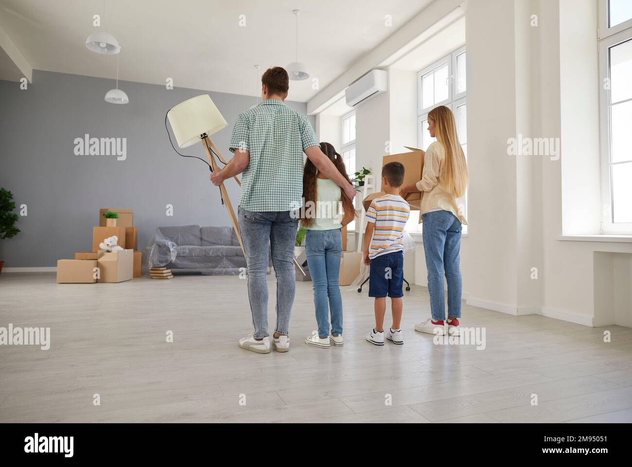 Happy young family with two children moves into their new spacious apartment house. Stock Photo