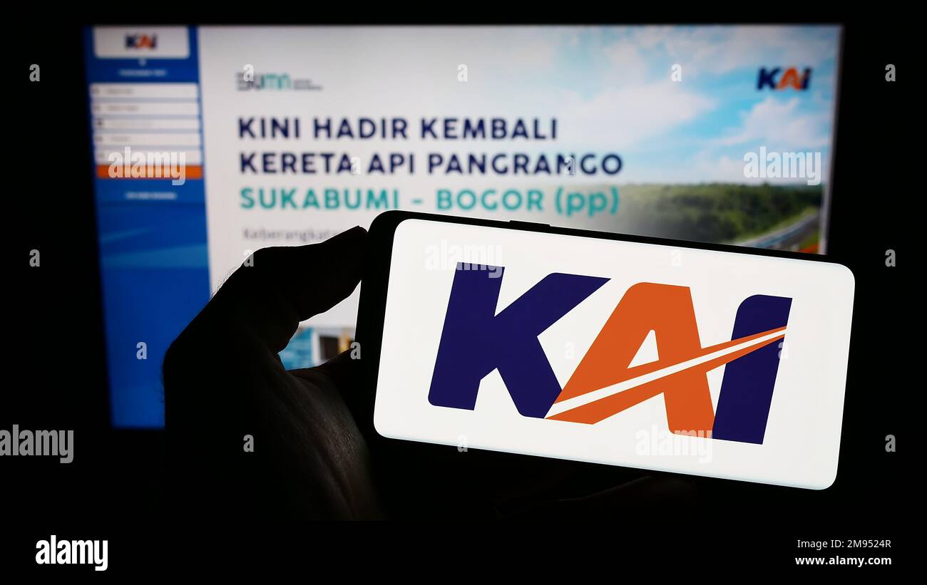 Person holding mobile phone with logo of Indonesian company PT Kereta