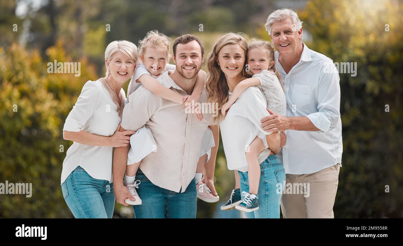 Portrait of multi-generation family standing together. Extended caucasian family smiling while spending time together at the park on a sunny day Stock Photo