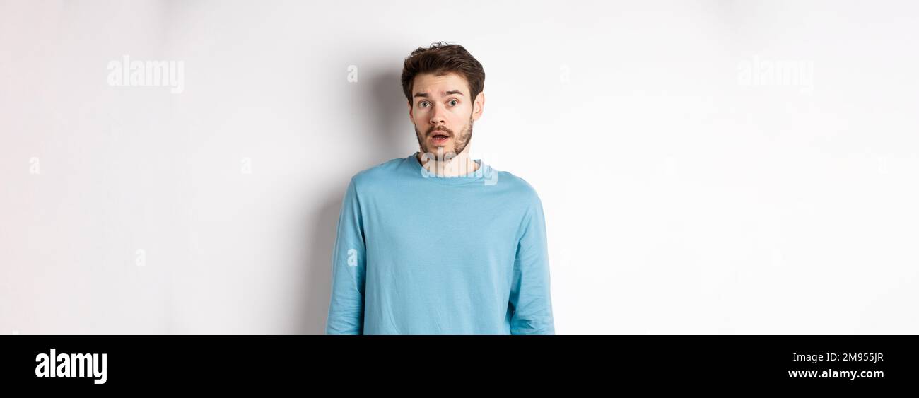 Confused caucasian guy drop jaw and stare startled at camera, standing