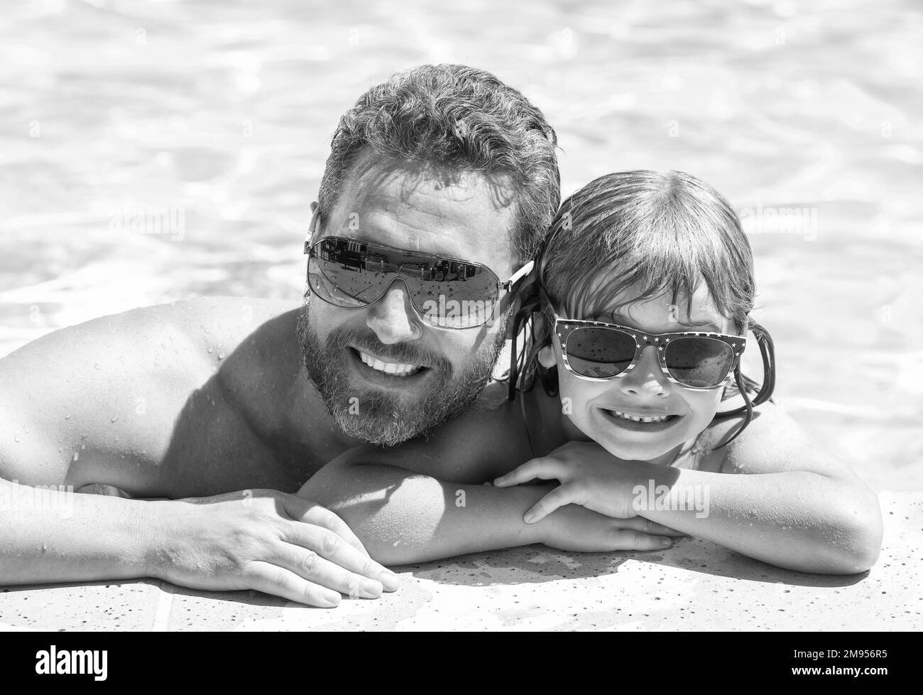 father and son wear glasses in swimming pool water. daddy with kid boy on spa resort. Stock Photo