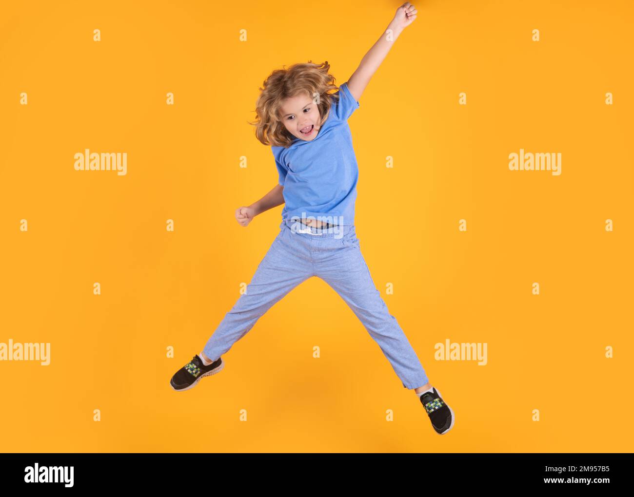 Full body of little child jump wear casual t-shirt and jeans isolated on yellow background. Stock Photo