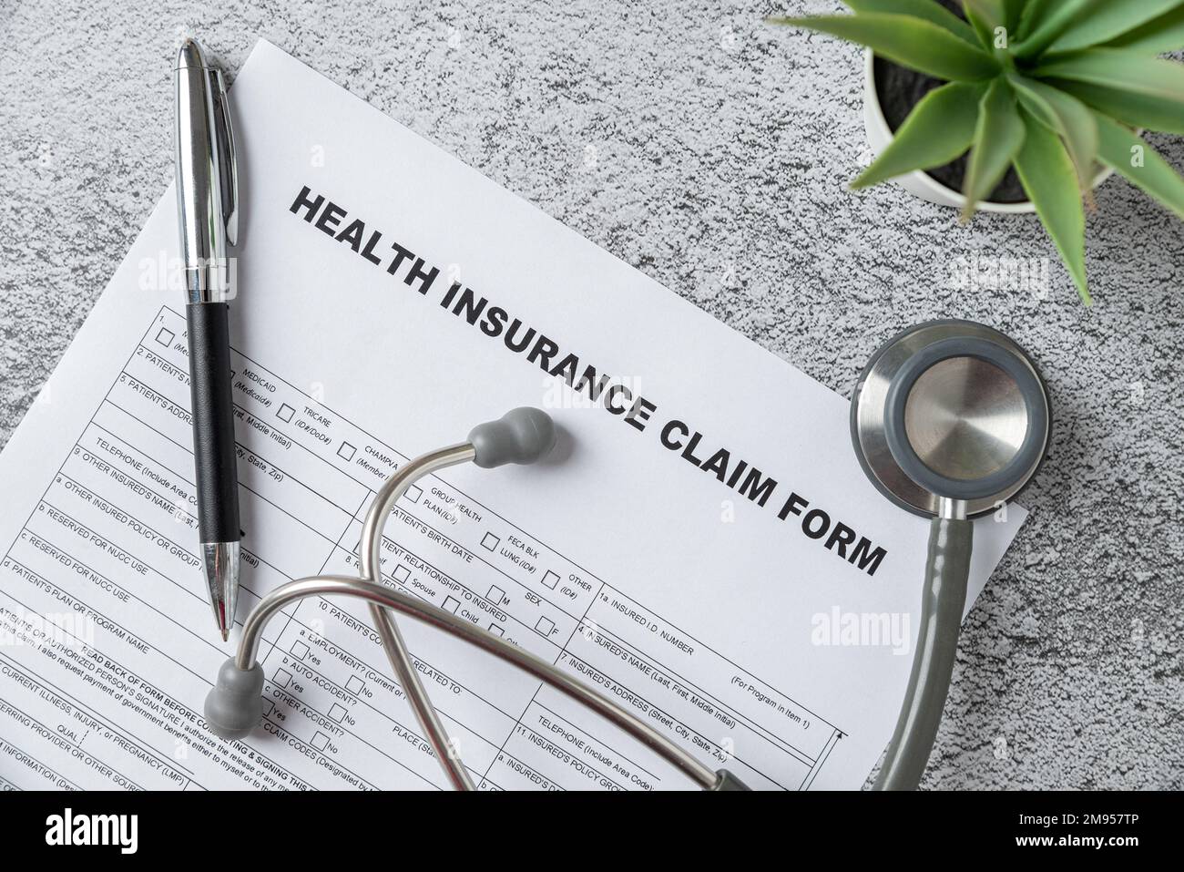 Top view of doctor stethoscope, pen and health insurance claim form on table Stock Photo
