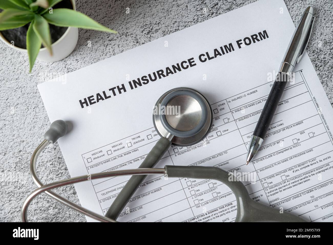 Top view of doctor stethoscope, pen and health insurance claim form on table Stock Photo