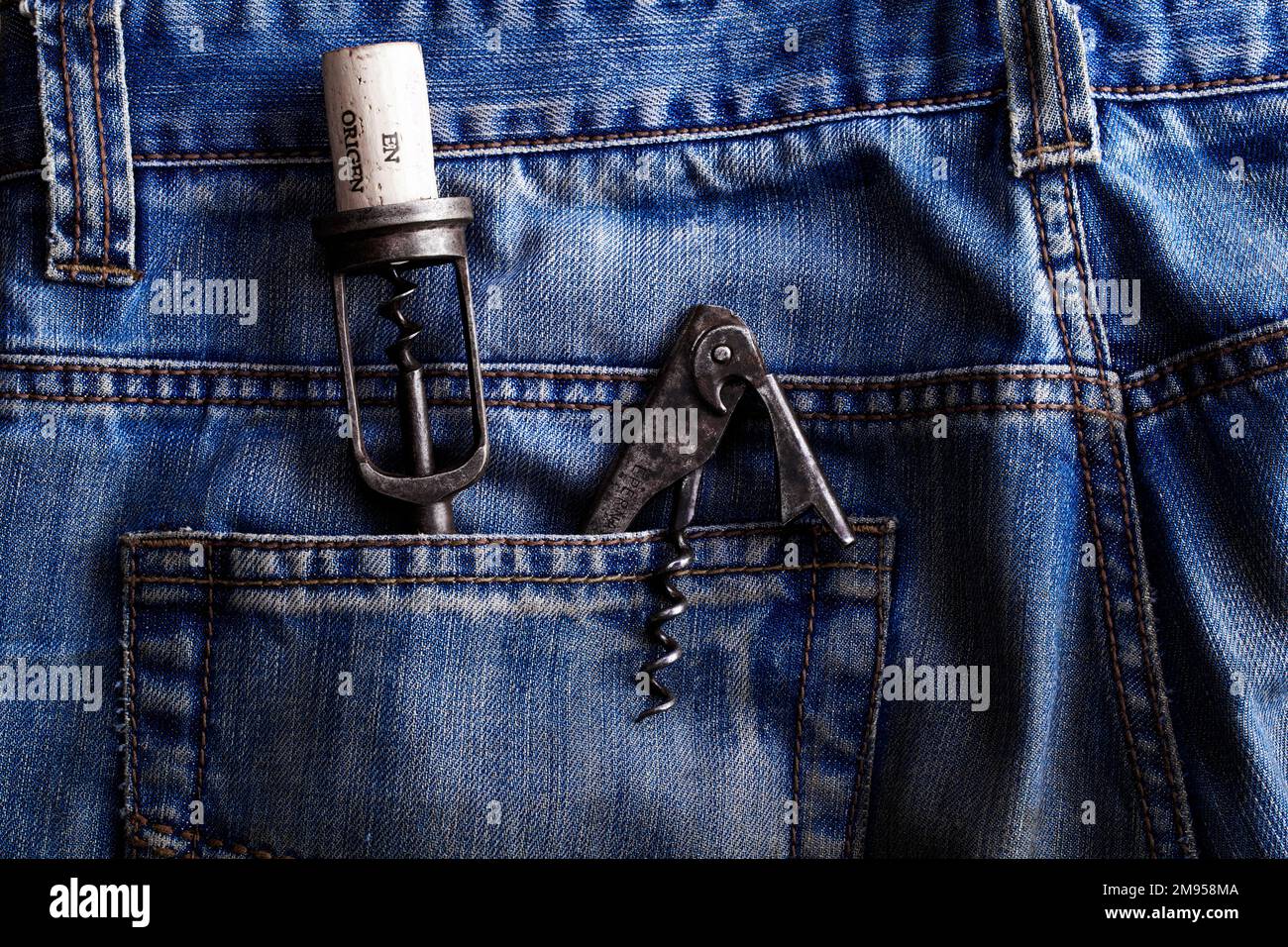 old corkscrew and bottle opener in the back pocket of an old pair of jeans Stock Photo