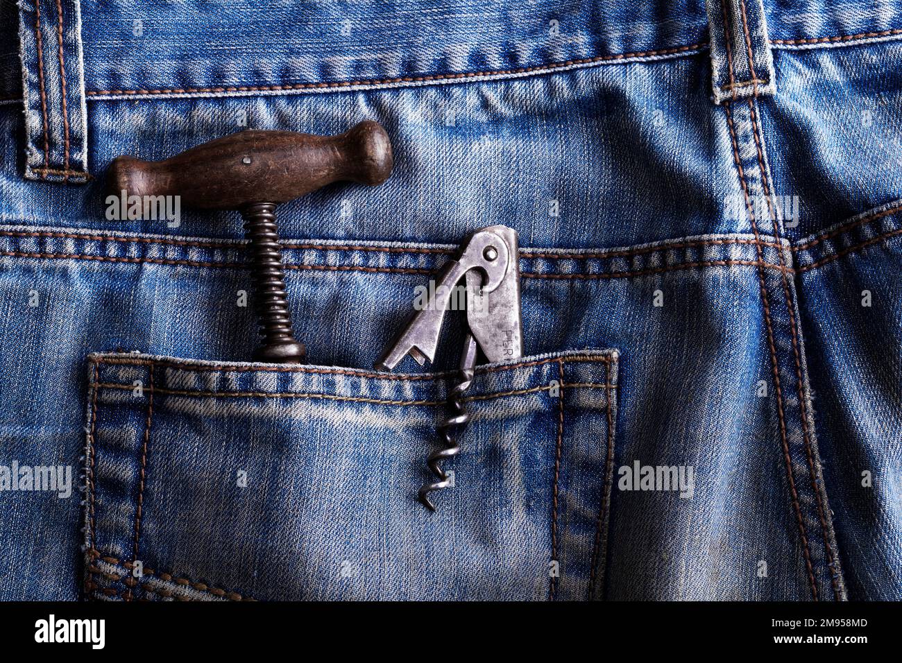 old corkscrew and bottle opener in a back pocket of blue jeans Stock Photo