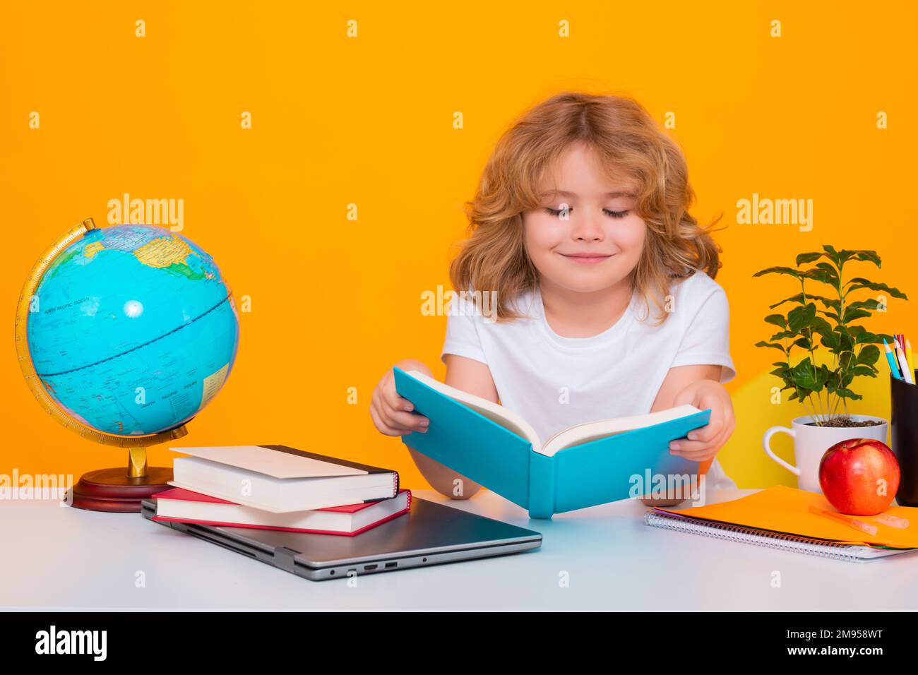 School kid reading book. Back to school. Portrait of cute child school boy, isolated on yellow studio background. School and education kids concept Stock Photo