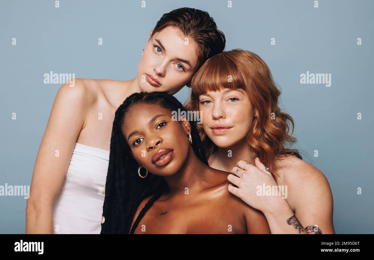 Women with different skin tomes looking at the camera in a studio. Group of confident young women feeling comfortable in their natural skin. Three bod Stock Photo
