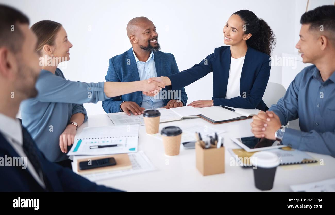 Team of smiling diverse business people shaking hands in office after meeting in boardroom. Group of happy professionals and colleagues using Stock Photo
