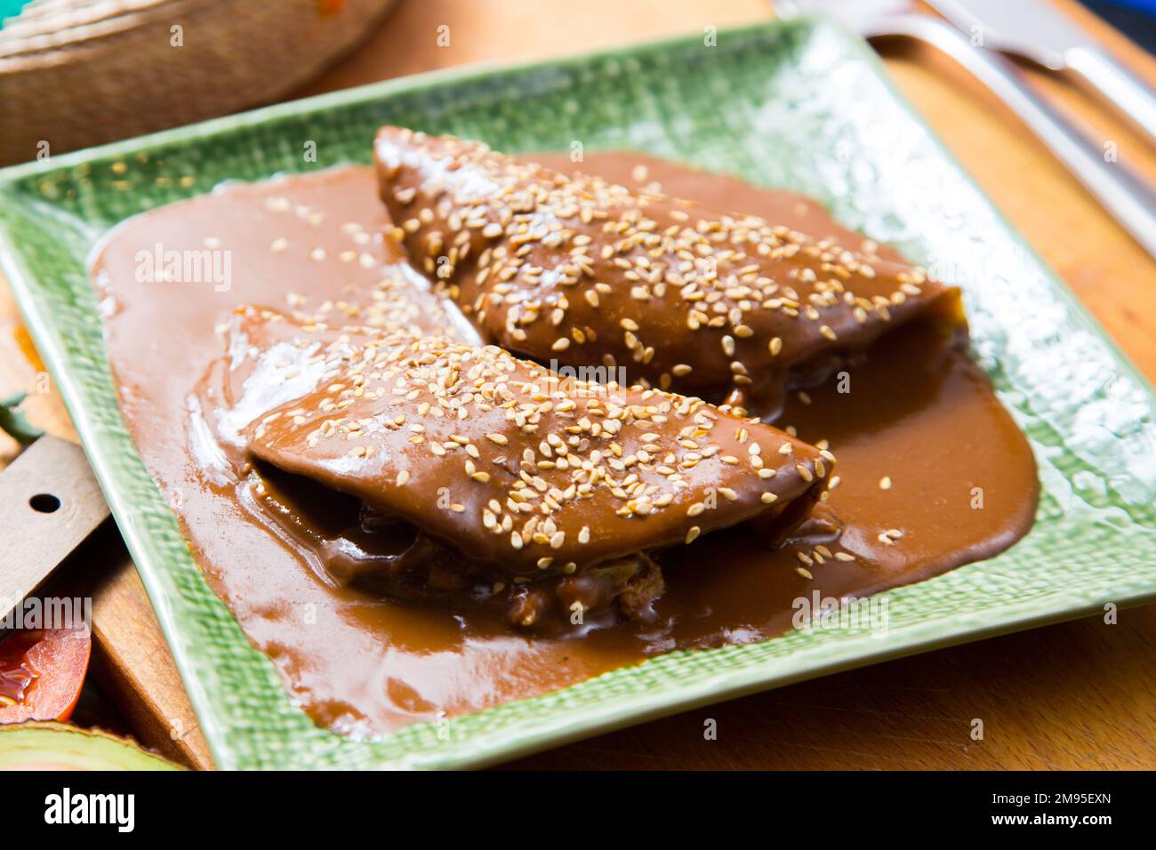 Mexican tacos covered with mole sauce. The term mole refers to various types of highly seasoned Mexican sauces made primarily from chili peppers and s Stock Photo
