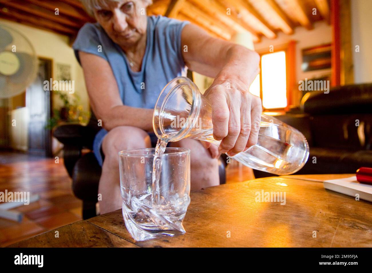 Senior citizens and heat wave: staying hydrated. Intense heat: old woman drinking water. Illustration, elderly people and hydration, dehydration risk Stock Photo