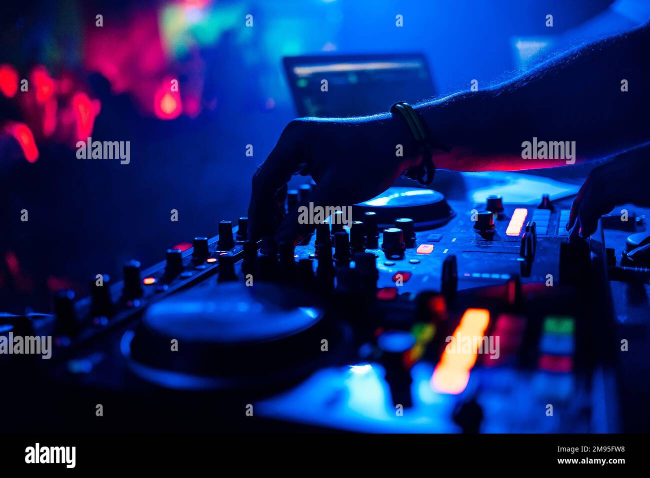DJ mixing music moving the controllers on the mixer in night club with