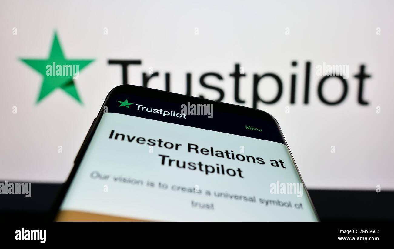 Mobile phone with website of review platform company Trustpilot Group plc on screen in front of business logo. Focus on top-left of phone display Photo Alamy