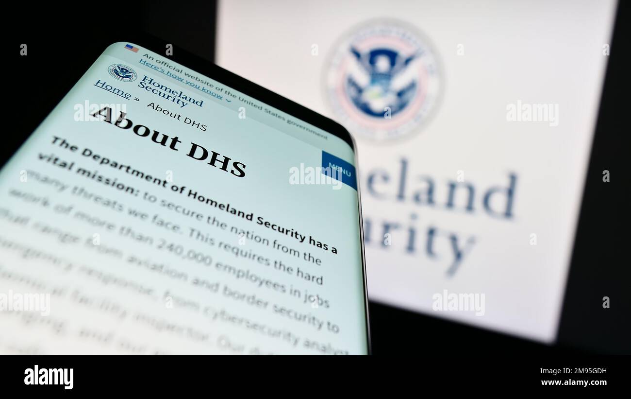 Smartphone with website of US Department of Homeland Security (DHS) on screen in front of seal. Focus on top-left of phone display. Stock Photo
