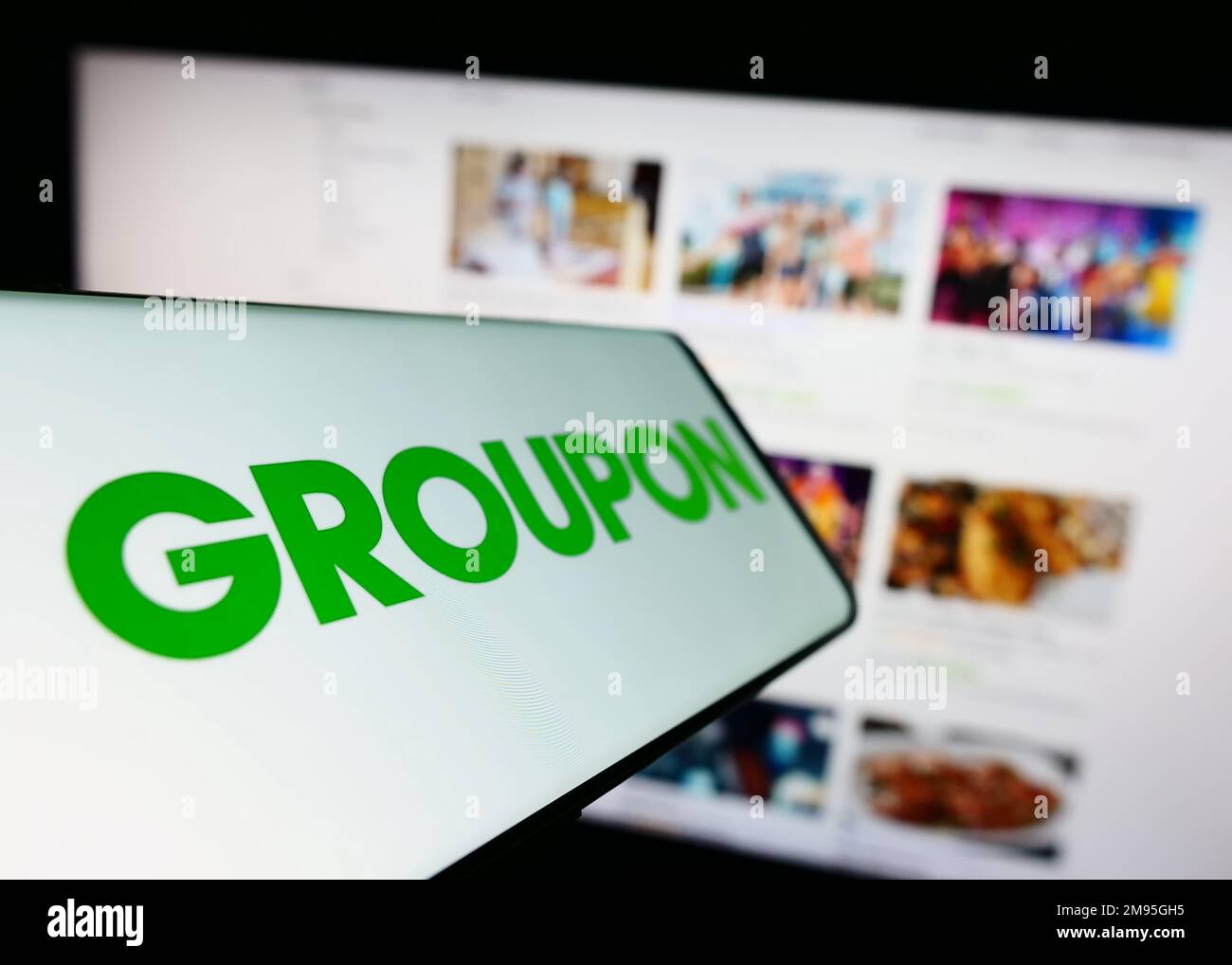 Cellphone with logo of American e-commerce company Groupon Inc. on screen  in front of business website. Focus on left of phone display Stock Photo -  Alamy