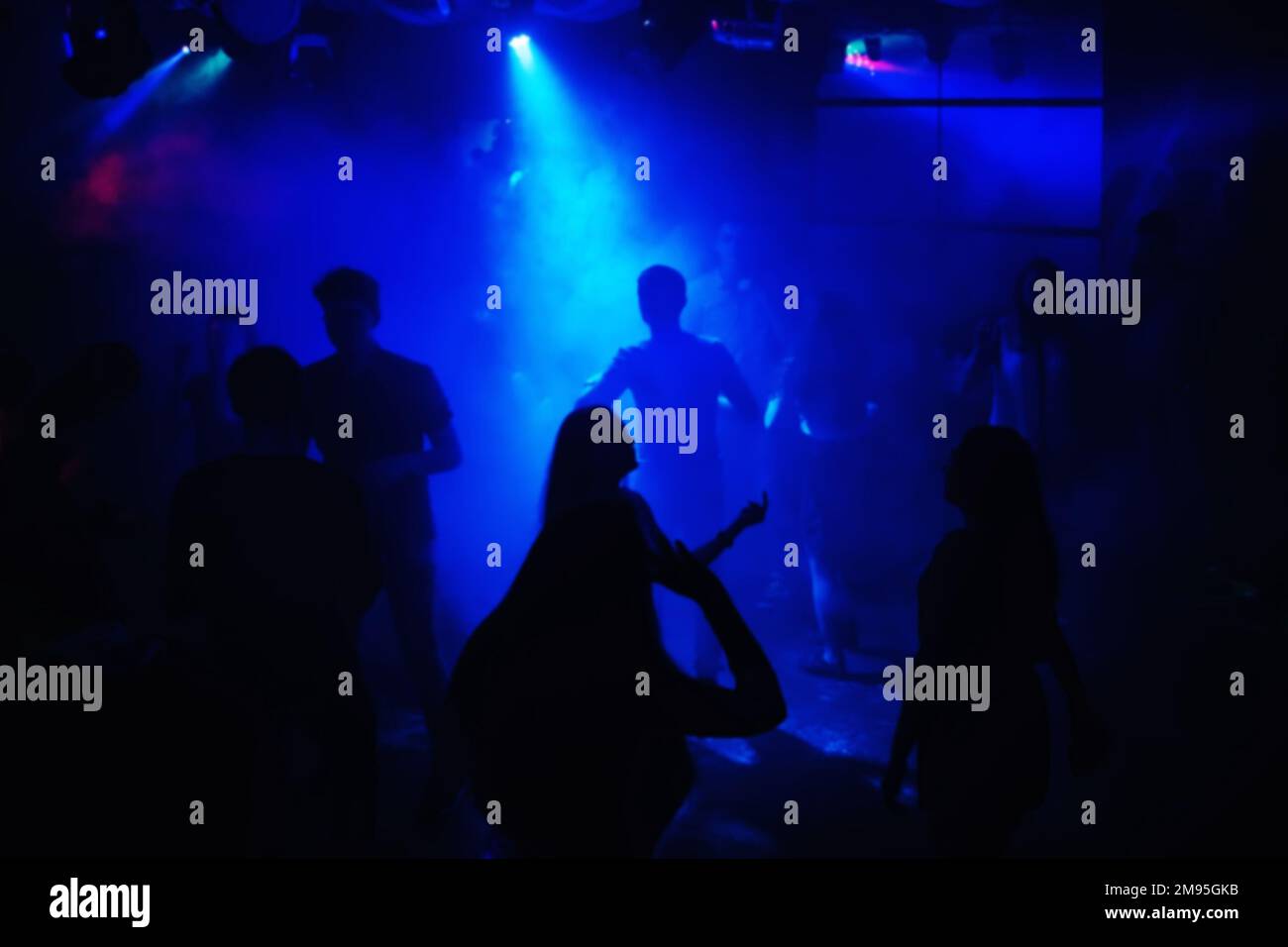 blurred people dancing on the dance floor at the event in a night club under the blue spotlights Stock Photo