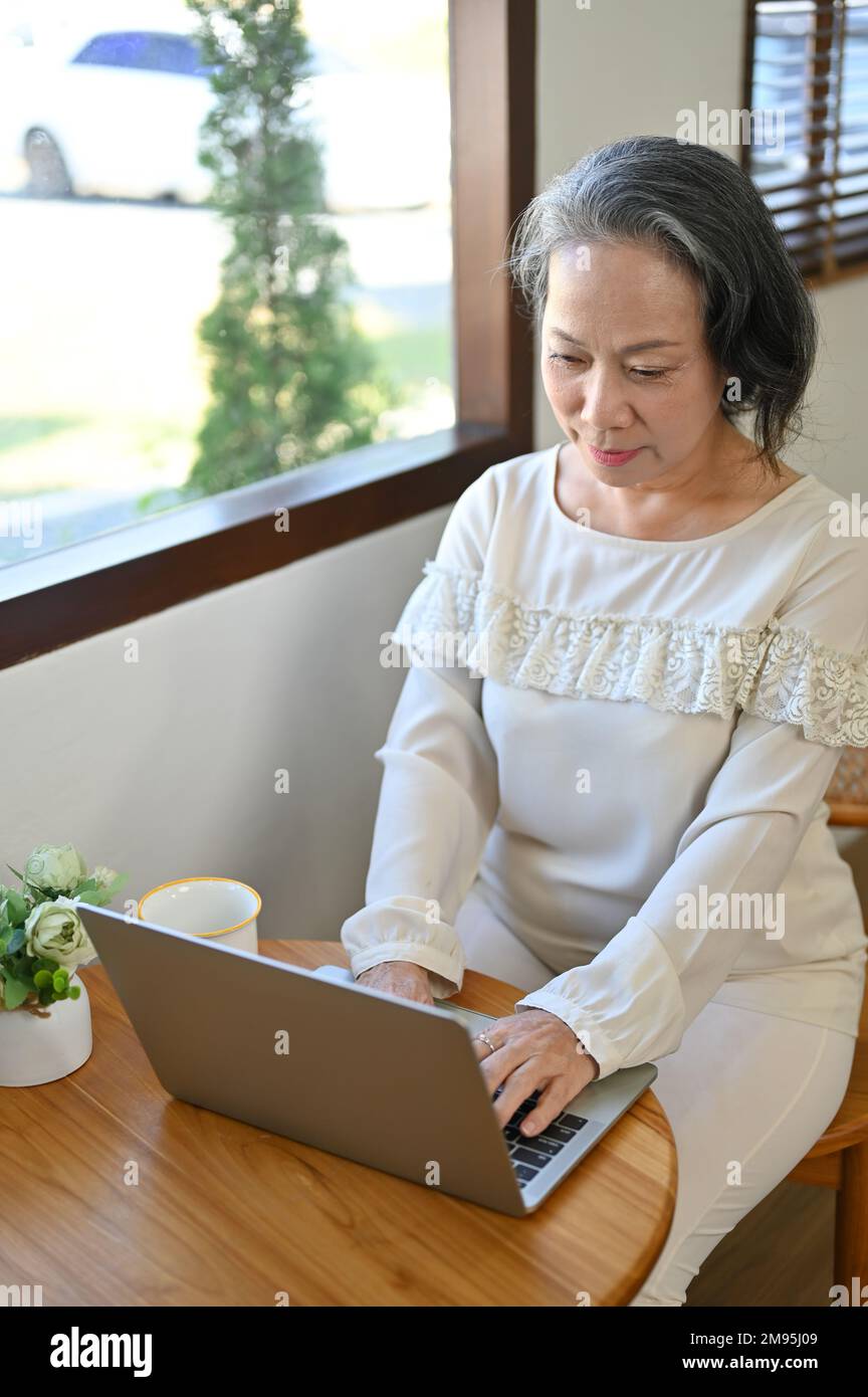 Concentrated and professional aged Asian businesswoman managing her