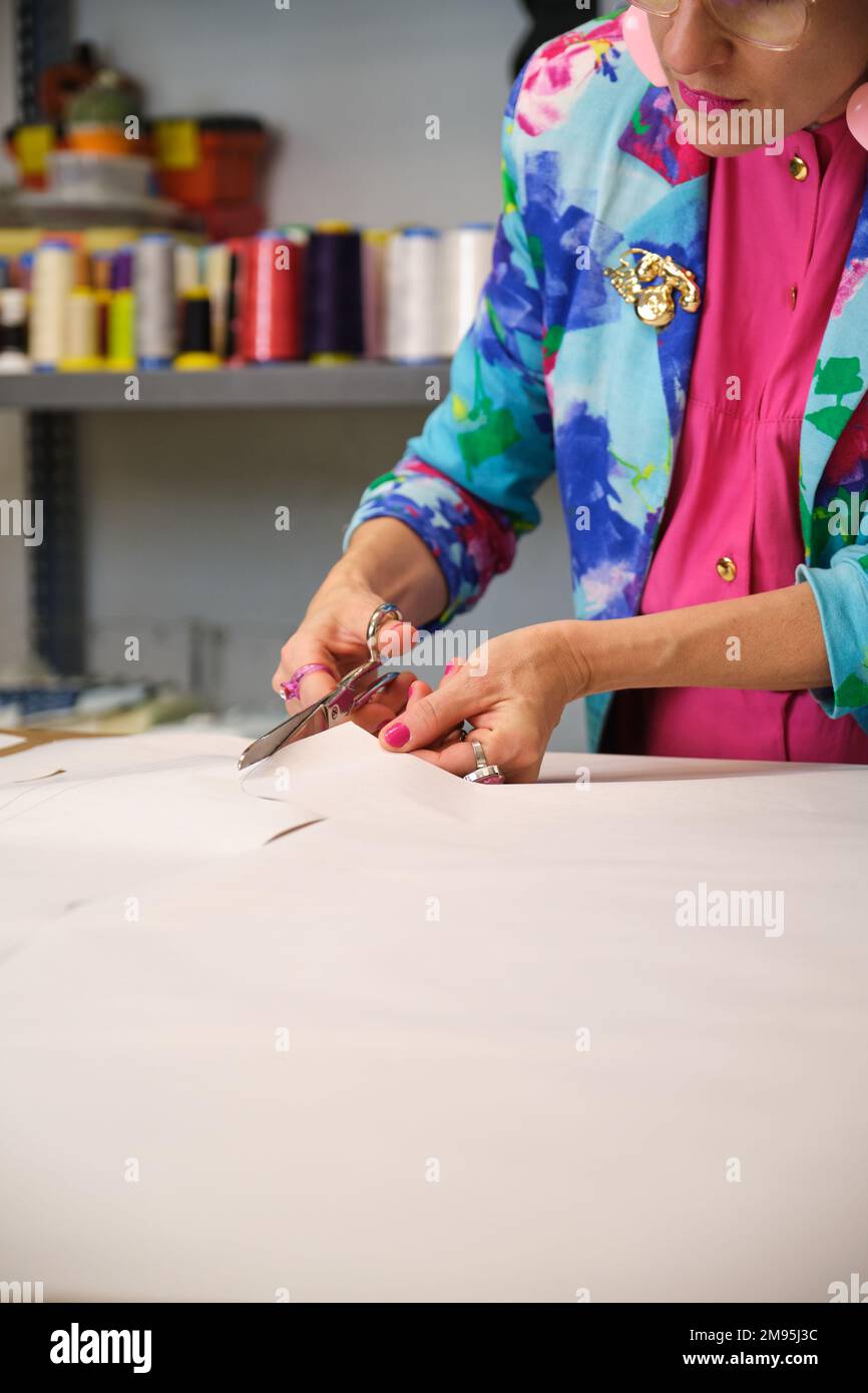 Dressmaker with colorfull clothes cutting sewing patterns. Stock Photo