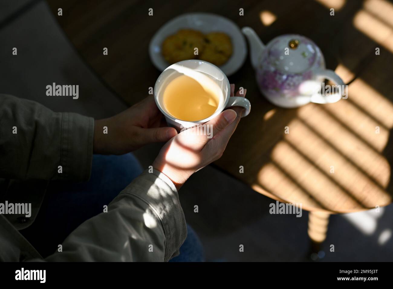 Hand Over Tea Top view, A woman's hands holding a cup of hot tea over blurred tea ...