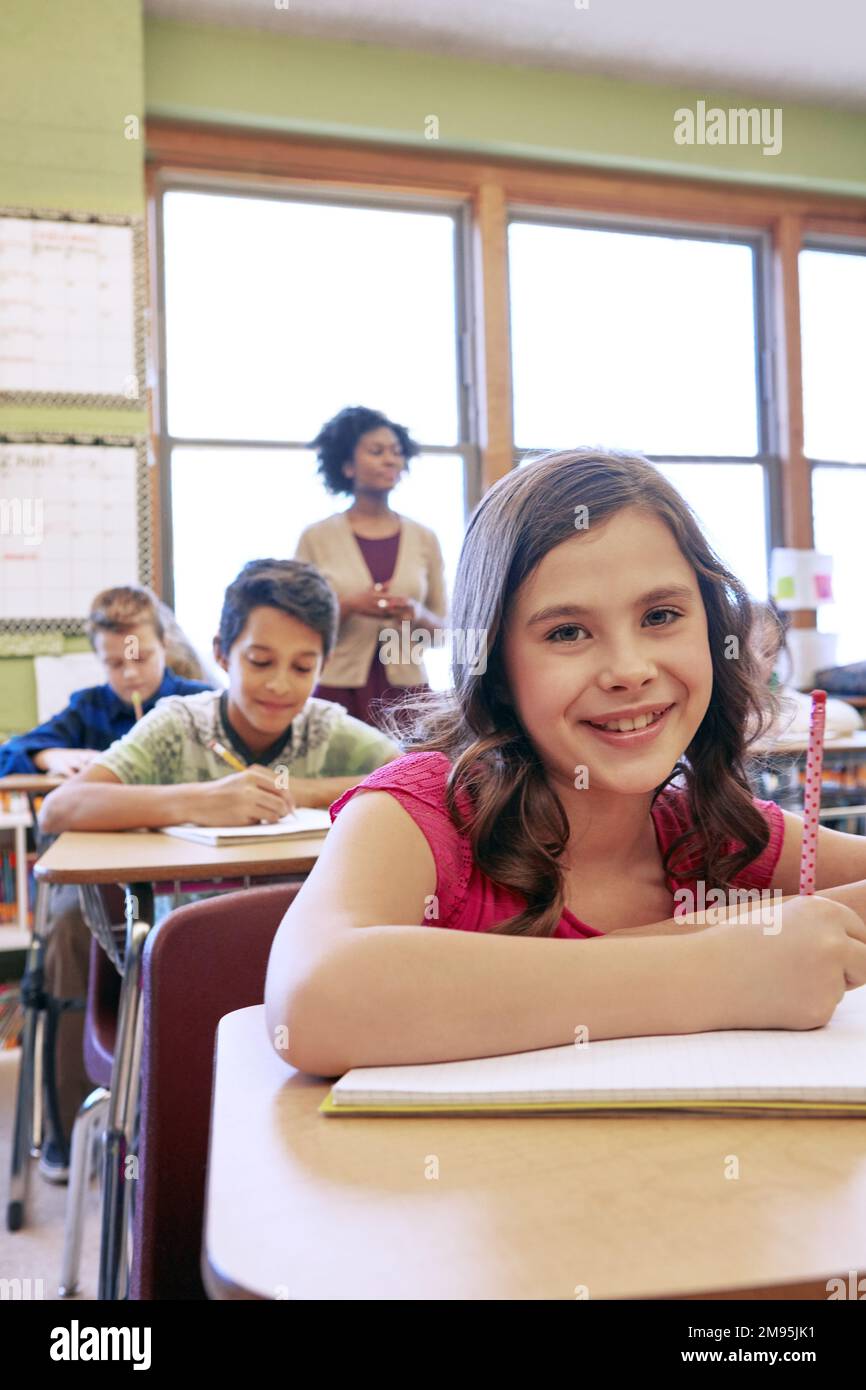 Happy, students and portrait of girl in classroom with notebook for lesson notes and knowledge. School kids, learning and development of middle school Stock Photo