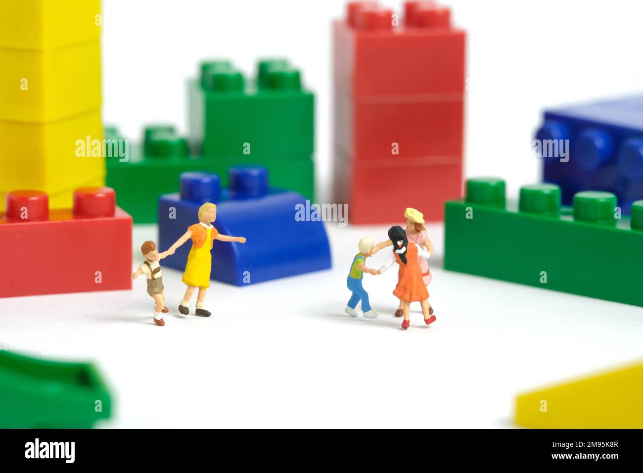Miniature people toy figure photography. Fun learning concept. Kids playing building block together. Isolated on white background. Image photo Stock Photo
