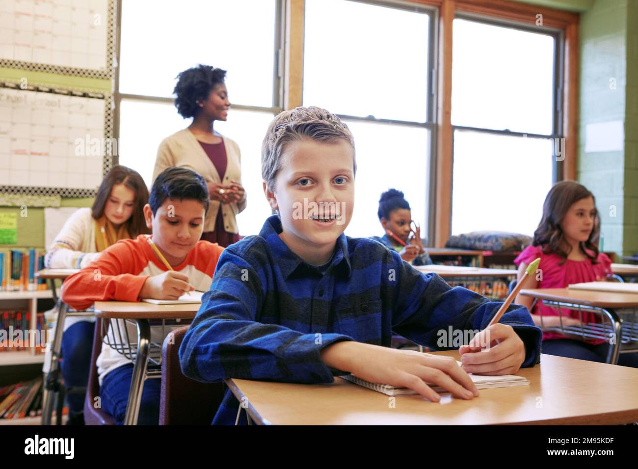 Education, boy and student portrait in classroom with notebook for lesson notes and knowledge. School kids, learning and development of middle school Stock Photo