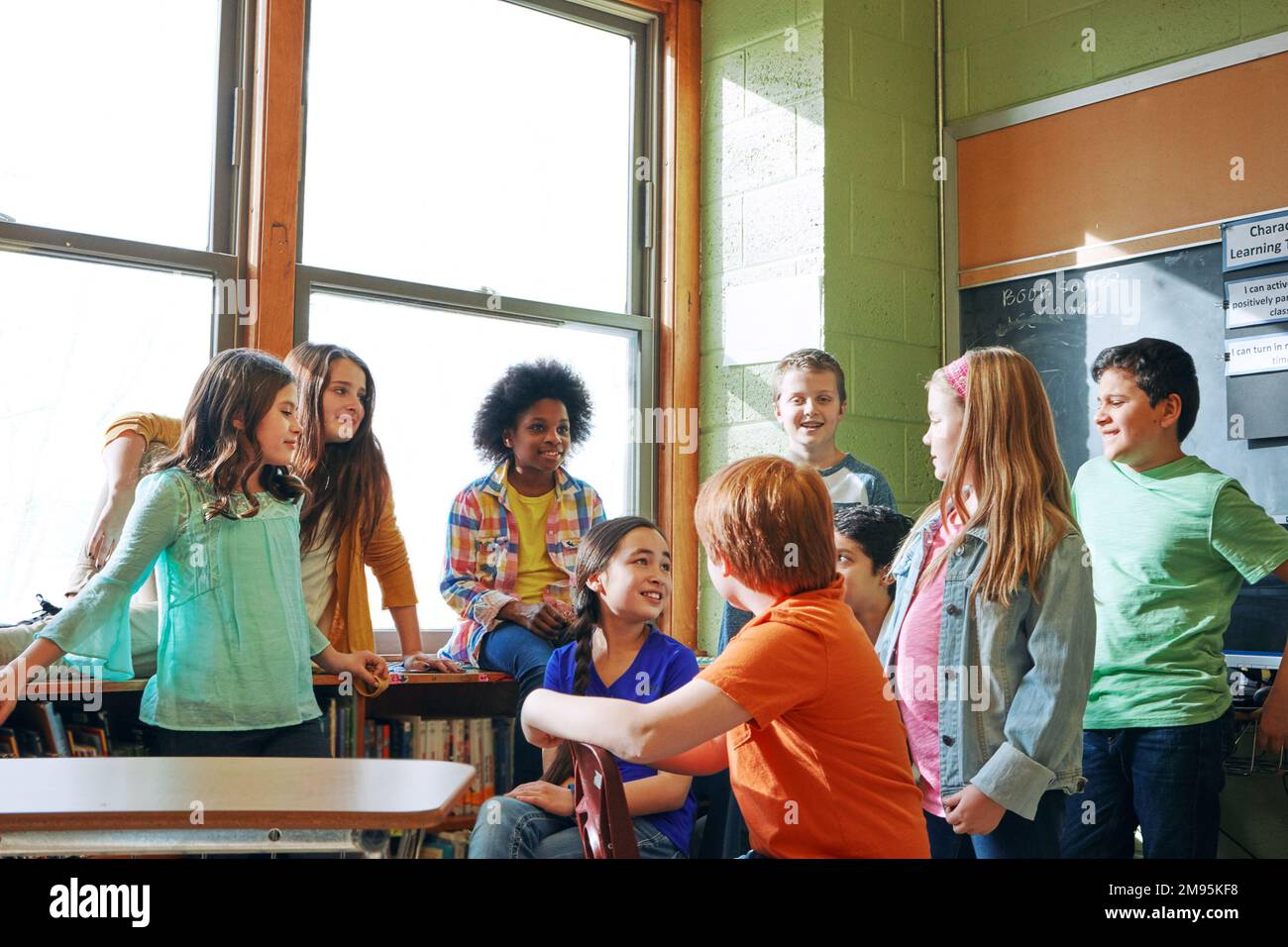 School, children and students talking in a classroom to learn, and study for knowledge and education. Diversity boy and girl group in class learning Stock Photo