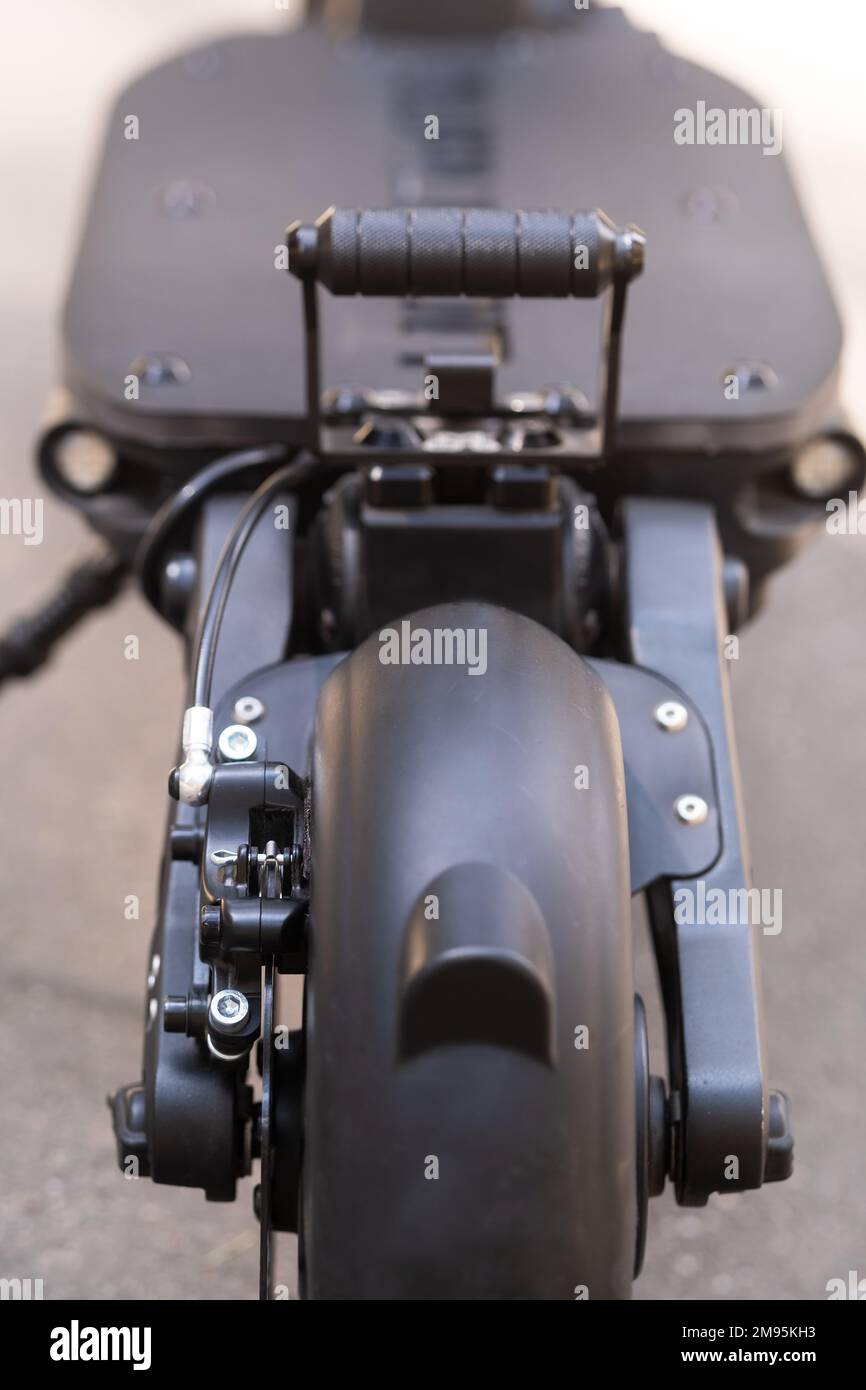 The back of the electric scooter with a foot rest on the asphalt