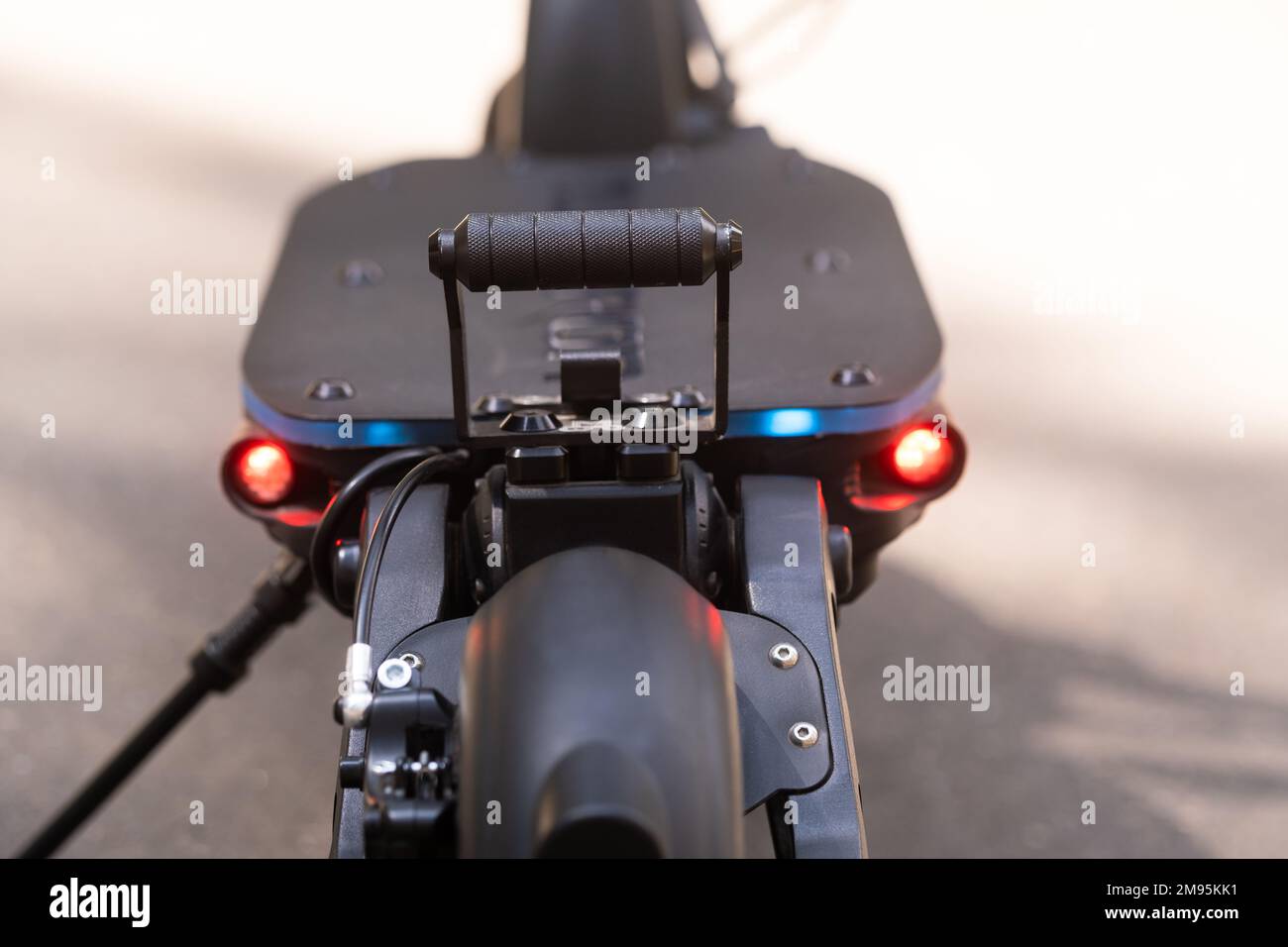 The back of the electric scooter with a foot rest on the asphalt