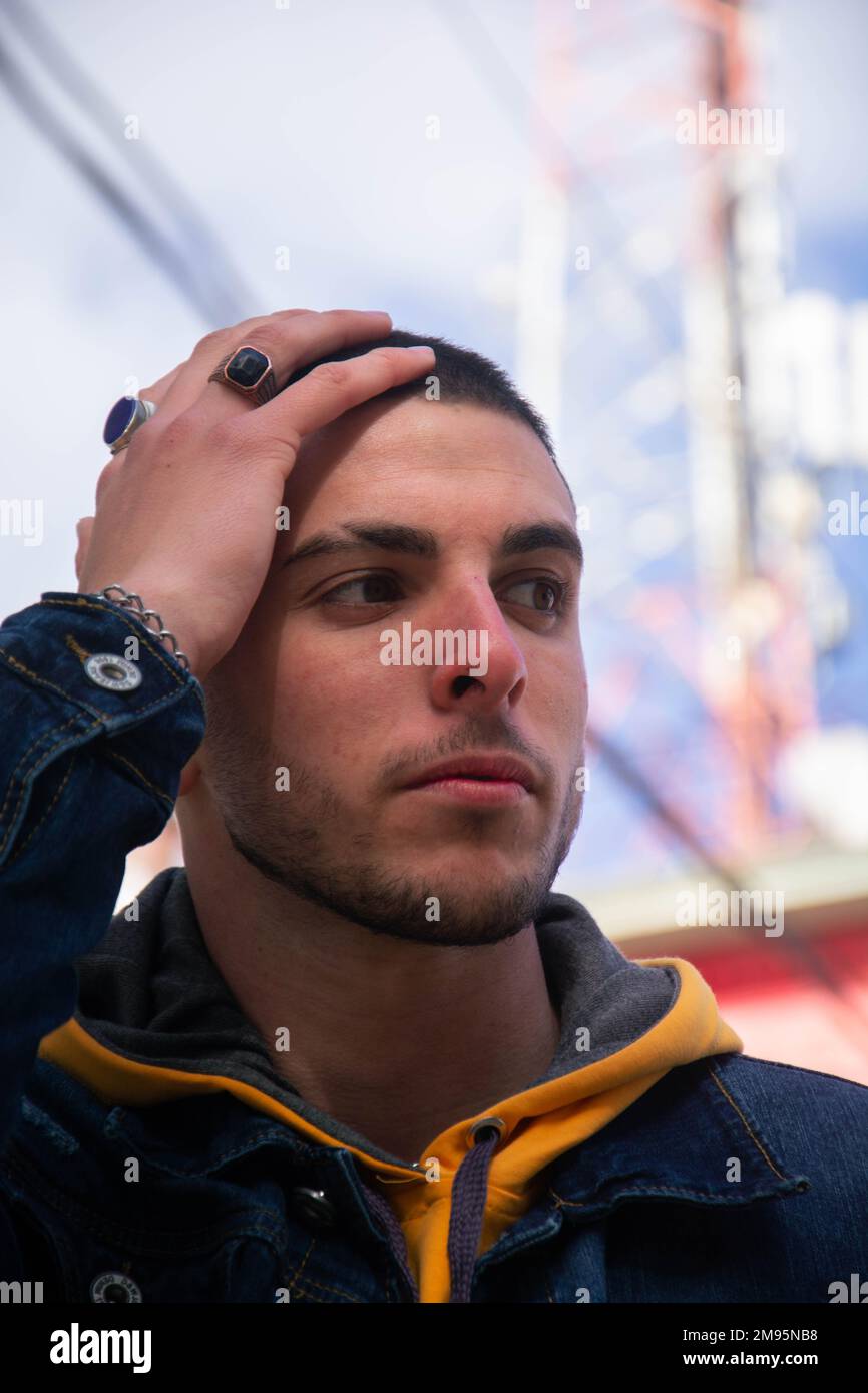 A vertical closeup of a young man touching his head. Stock Photo