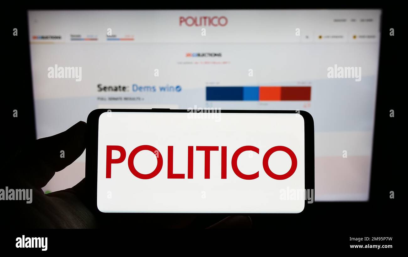 Person holding smartphone with logo of US political newspaper company Politico LLC on screen in front of website. Focus on phone display. Stock Photo