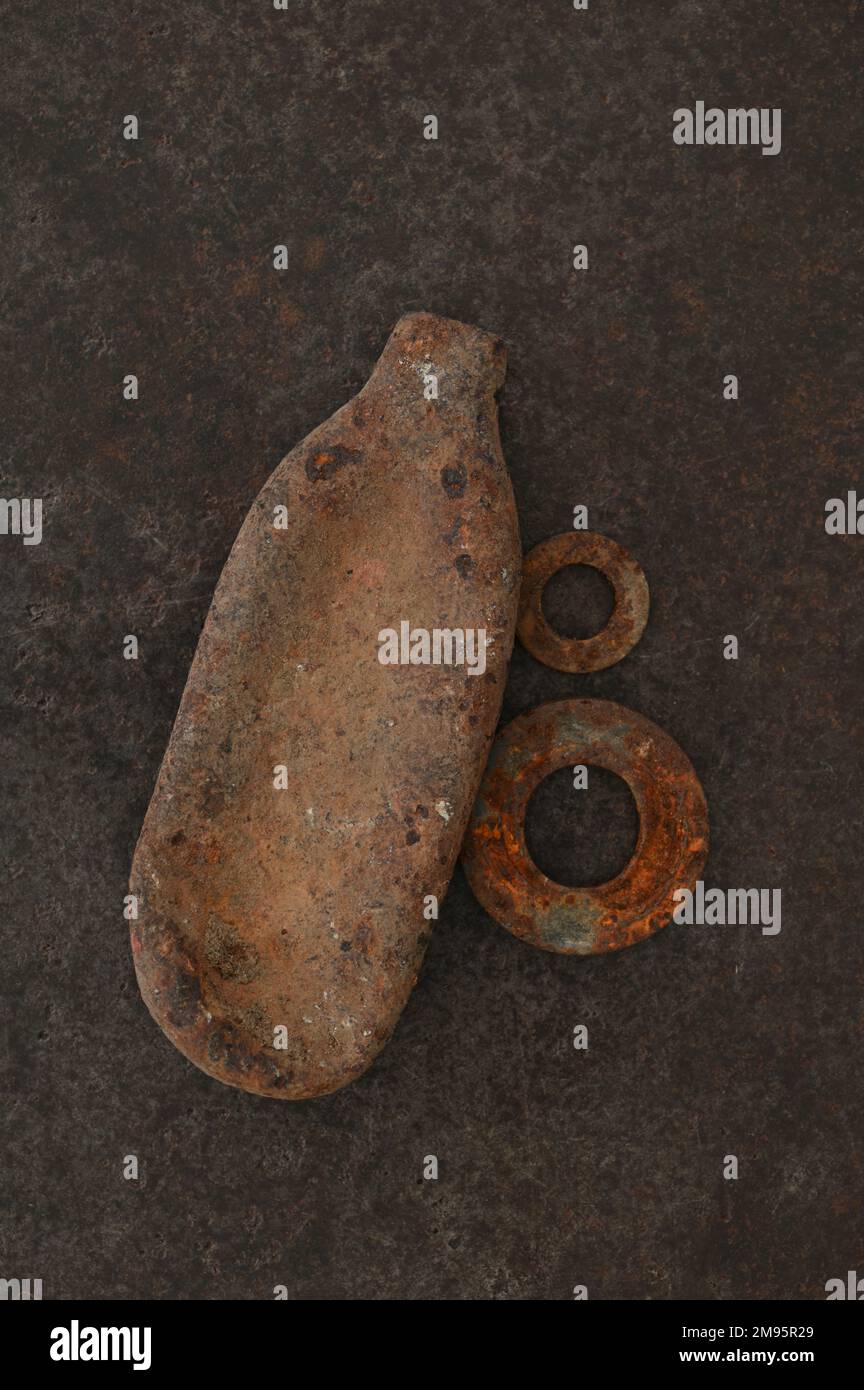 Squasahed and rusty gas canister from airgun lying with two rusty metal washers on old leather Stock Photo