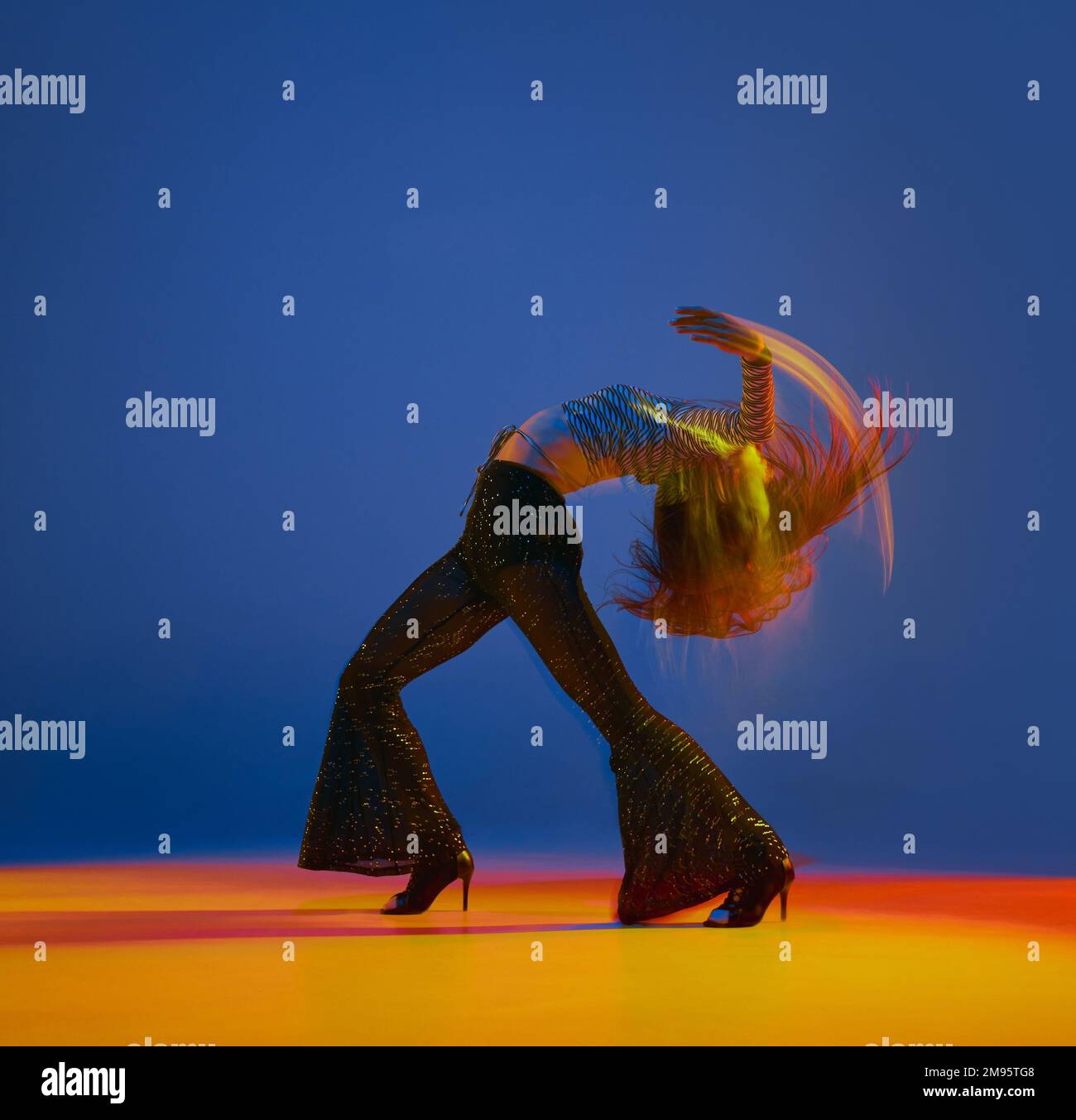 Openness. Portrait of young girl dancing heels dance in stylish clothes over blue background in neon with mixed lights. Concept of modern dance style Stock Photo