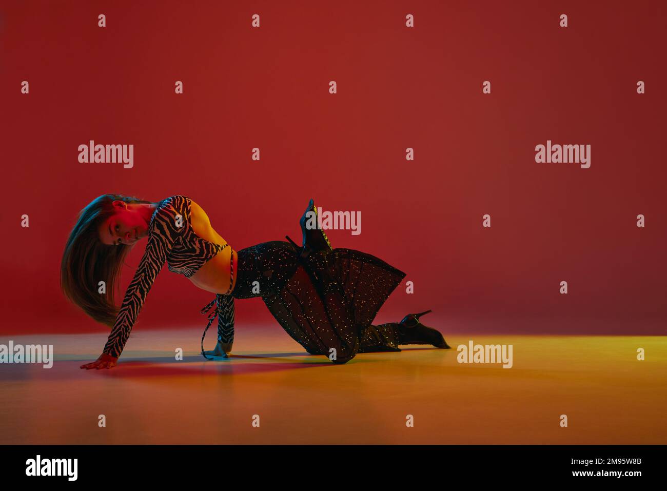 Flexibility. Portrait of young girl dancing heels dance over red background in neon light. Concept of modern dance style Stock Photo